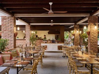 Przestronna otwarta restauracja z drewnianymi belkami, kamiennymi kolumnami oraz wieloma krzesłami i stołami.