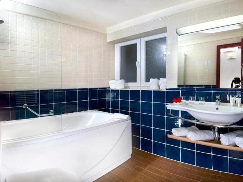 Moderne badkamer met bad, wastafel en blauw-witte tegels.