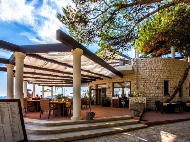 Hotelterras met zuilen, stoelen en tafels onder een blauwe lucht.