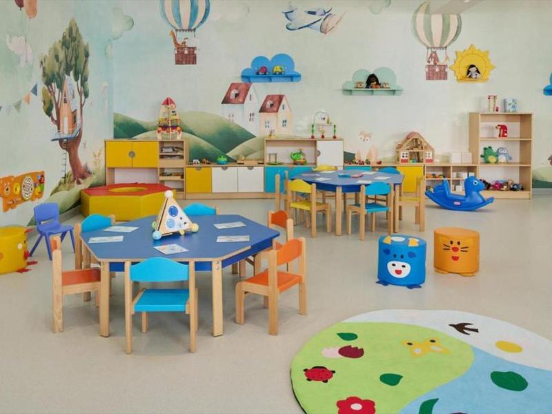 Kleurrijke kleuterklas met kindertafels, stoelen en muurschilderingen