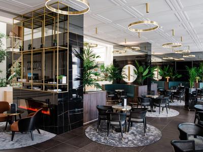 Modern hotelrestaurant met stijlvolle inrichting, ronde tapijten en gouden verlichtingsarmaturen.