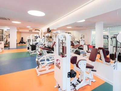 Bright gym with modern equipment and multicolored flooring.
