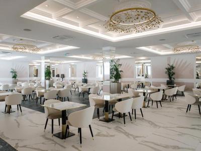 Large elegant dining area with white tables, chairs, and chandeliers.