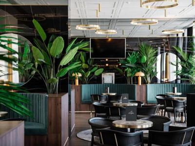 Modern restaurant interieur met planten en donker meubilair.