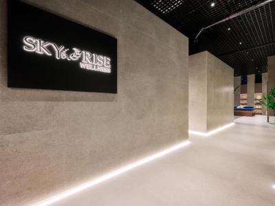 Moderne hotelgang met LED-verlichting en SKY & RISE-logo aan de muur.