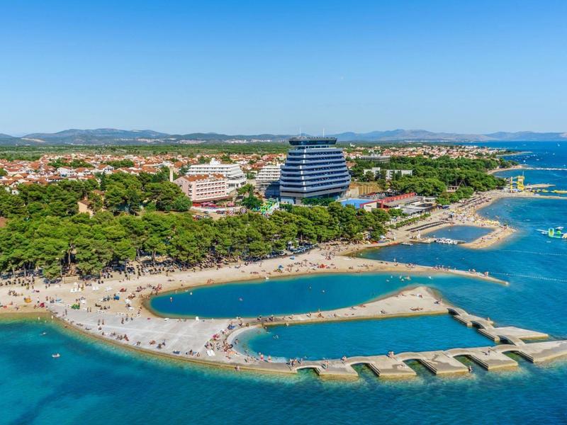 Luchtfoto van een strand met populaire ligbedden en hotels aan zee.