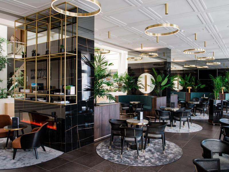 Modern hotelrestaurant met stijlvolle inrichting, ronde tapijten en gouden verlichtingsarmaturen.