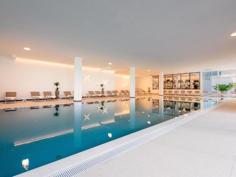 Licht binnenzwembad met zuilen en zithoek in een modern hotel.