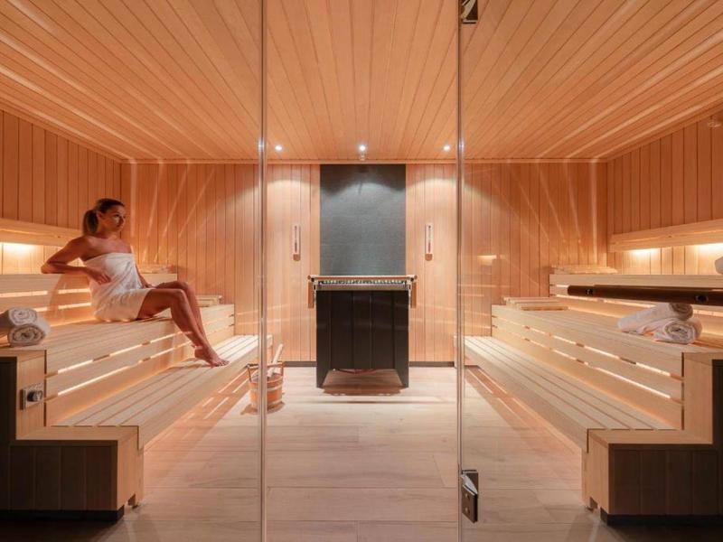 Moderne sauna met houten wanden, banken en een vrouw die ontspant.