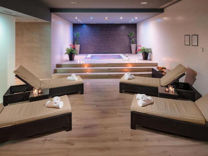 Ontspanningsruimte met ligstoelen, warm licht en decoratieve planten.