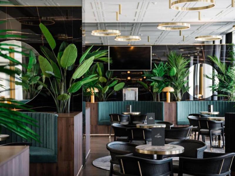 Modern restaurant interieur met planten en donker meubilair.