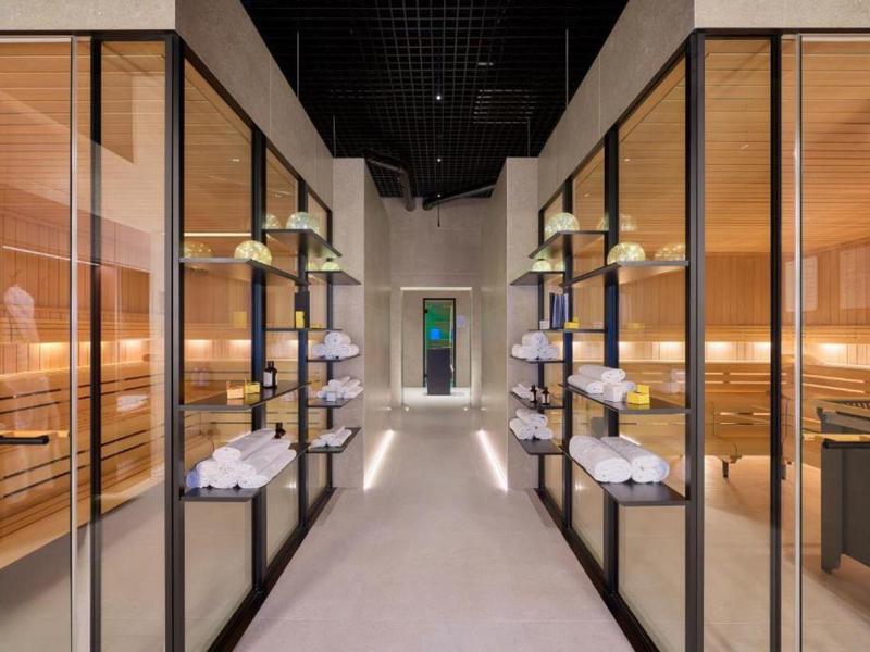 Moderne wellnessruimte met inloopsauna's en handdoeken op planken.