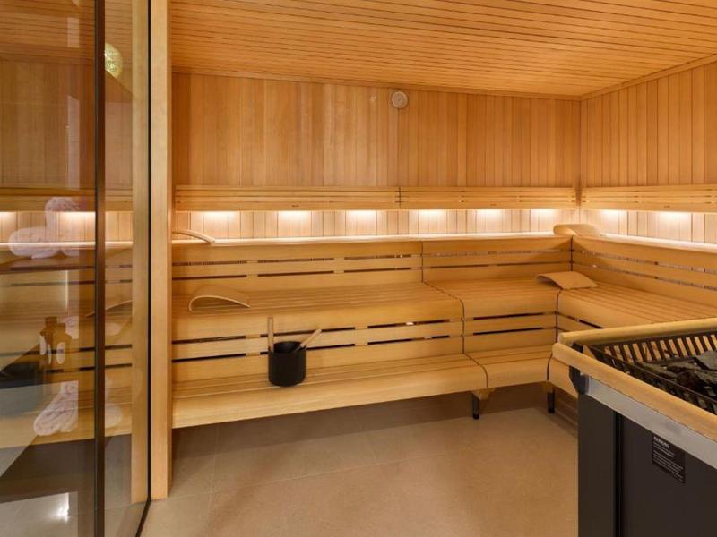 Saunaruimte met houten banken en saunakachel, warm verlicht en gezellig.