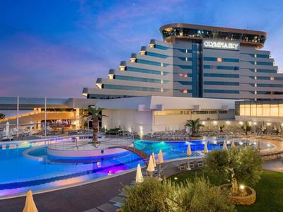 Hotel moderno con design a gradoni e piscina illuminata al tramonto.