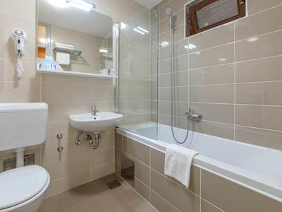 Modern bathroom with bathtub, sink, toilet, and large light-colored tiles.