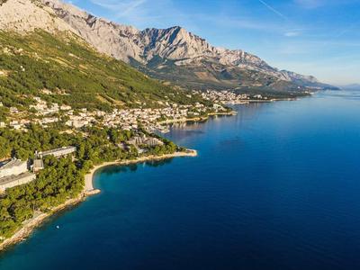 Pohled na pobřeží s horami, lesy a několika hotely podél vody.