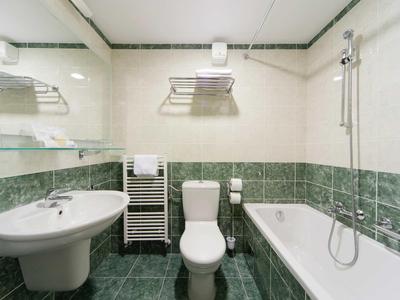 Moderní koupelna s toaletou, umyvadlem, vanou a vyhřívaným věšákem na ručníky.