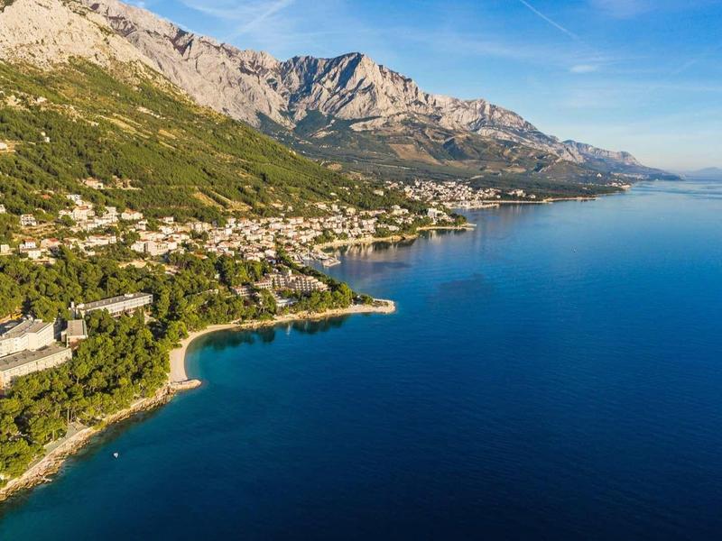 Pohled na pobřeží s horami, lesy a několika hotely podél vody.