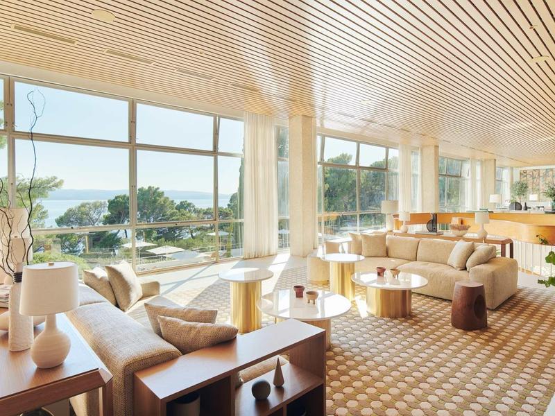 Světý, moderní hotelový pokoj s velkým panoramatickým oknem a výhledem do přírody.