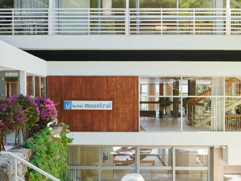 Moderní hotelové nádvoří s bílými zábradlími a dřevěnými detaily za denního světla.