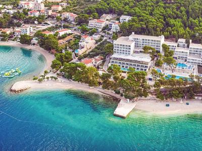 Vista aérea de un resort costero con playa de arena y agua azul clara.
