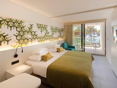 Chambre d'hôtel moderne avec lit double, décoration murale et balcon avec vue.