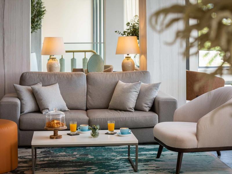 Salon moderne avec canapé gris, fauteuils blancs et table basse avec boissons.