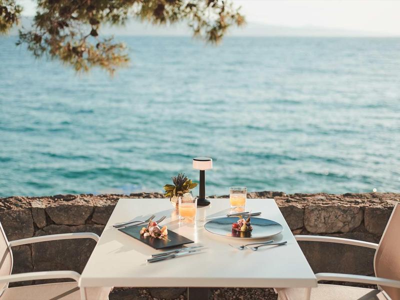 Une table dressée pour deux avec vue sur la mer par une journée ensoleillée.