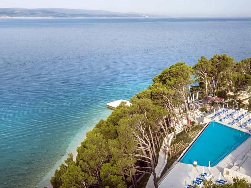 Piscine d'hôtel sur la côte avec vue sur la mer bleue et les arbres verts