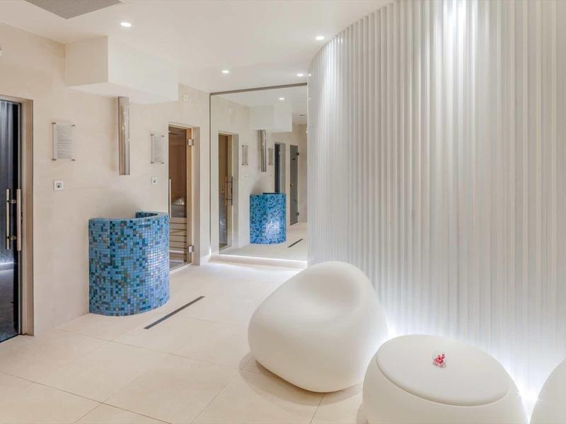 Espace bien-être moderne et lumineux avec sculpture courbe et éclairage indirect.