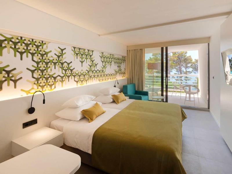 Chambre d'hôtel moderne avec lit double, décoration murale et balcon avec vue.