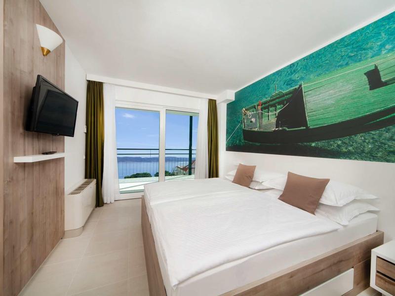 Nowoczesny pokój hotelowy z łóżkiem podwójnym, dużym obrazem morza i widokiem na morze przez okno.