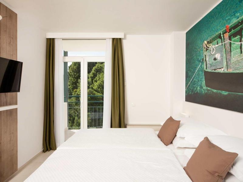 Nowoczesny pokój hotelowy z podwójnym łóżkiem, dużym obrazem na ścianie i telewizorem.