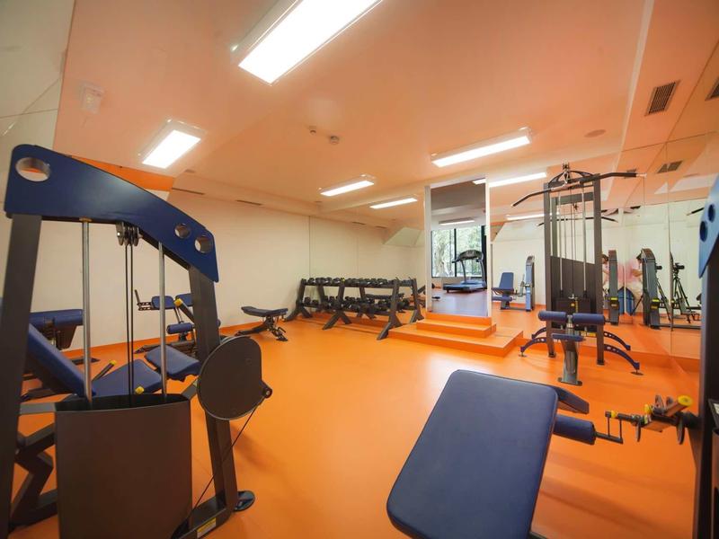 Siłownia z różnymi urządzeniami i pomarańczową podłogą.