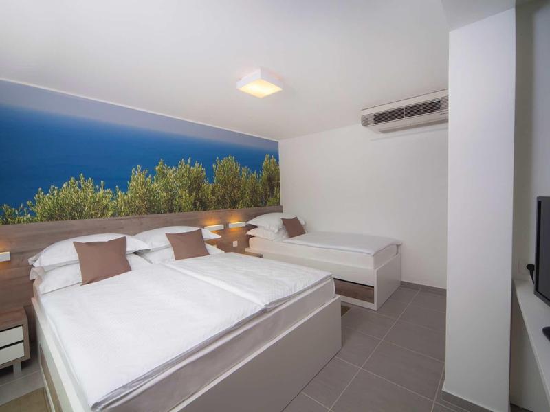 Nowoczesny pokój hotelowy z dwoma dużymi łóżkami, muralem drzew i klimatyzacją.