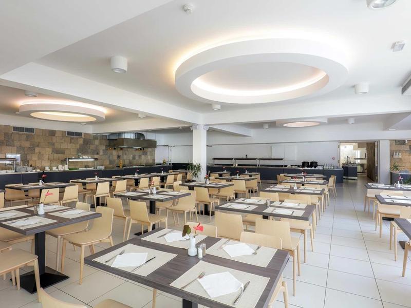 Nowoczesna, jasna jadalnia z wieloma starannie ułożonymi drewnianymi stołami i krzesłami.