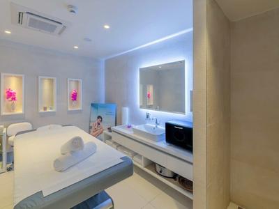 Lichte wellness- of behandelkamer met massagetafel, zitplaatsen en rustgevende verlichting.