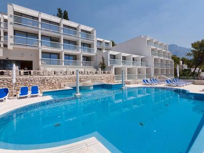 Moderner Hotelpool mit blauen Liegestühlen und weißem Gebäude im Hintergrund