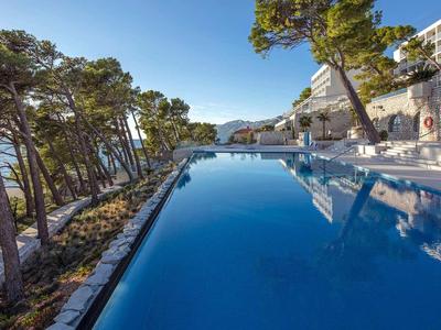 Infinity-Pool mit Blick auf das Meer und umliegende Bäume an einem sonnigen Tag.