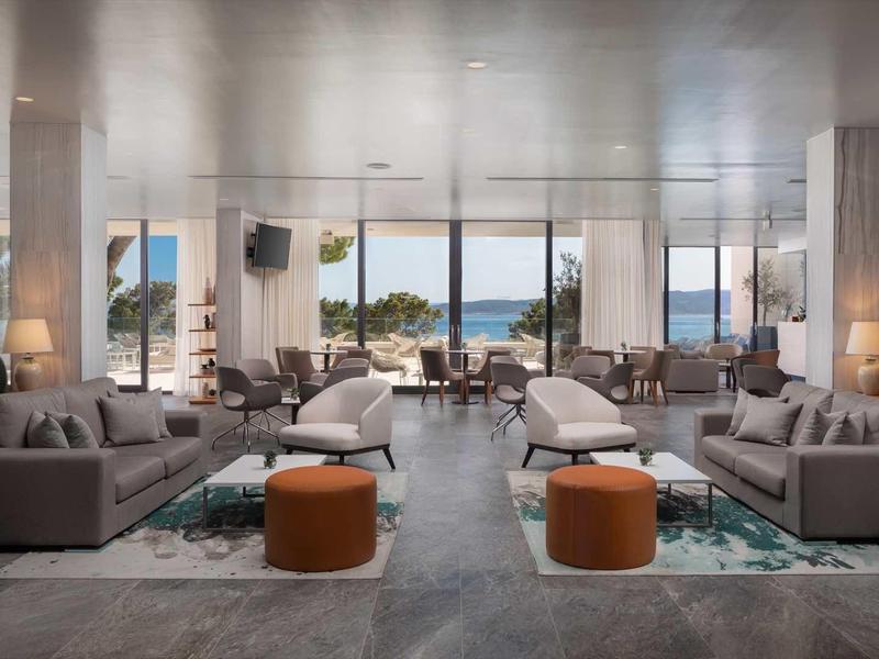 Moderne hotel lobby met grote ramen met uitzicht op zee en comfortabele zitgedeeltes.