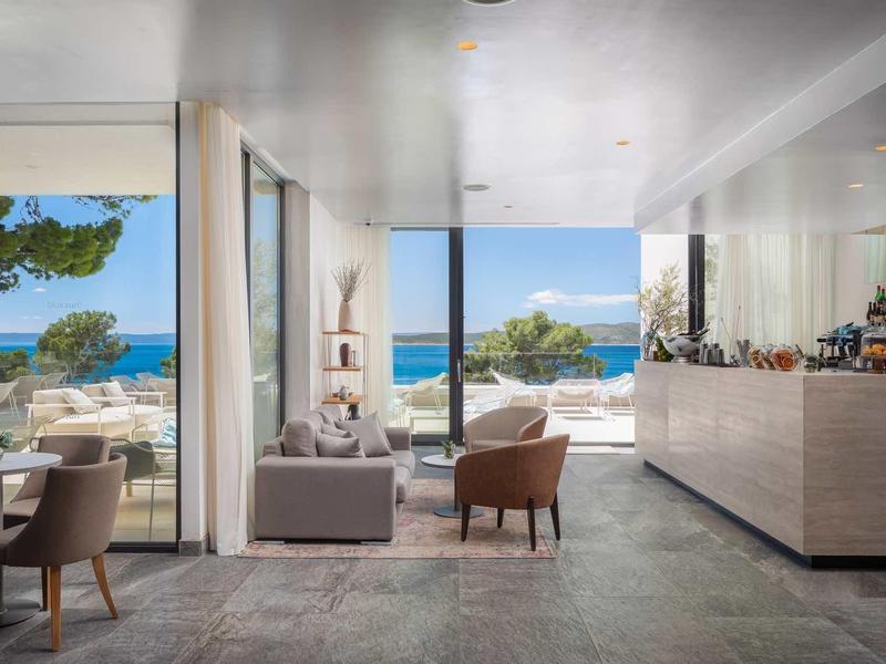 Moderne lounge met uitzicht op zee en zwembad, meubels in neutrale tinten.