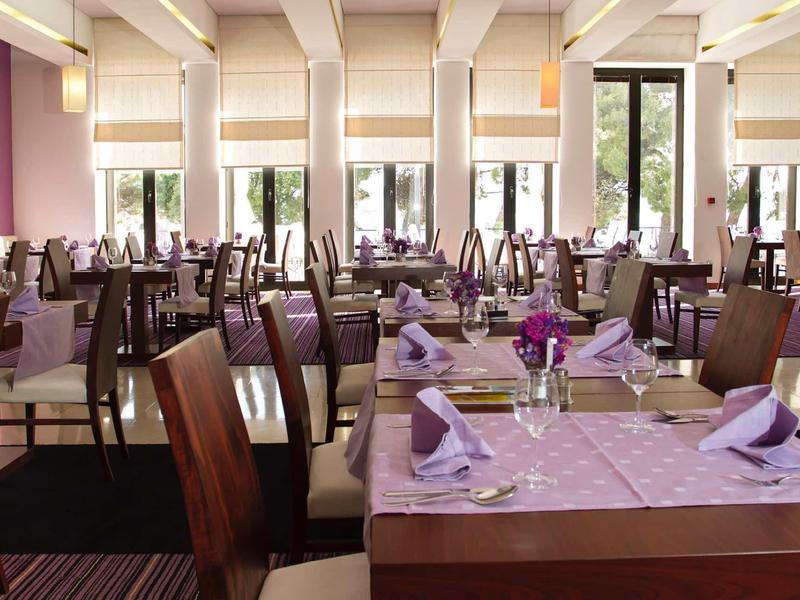 Světlá restaurace s prostřenými stoly, židlemi a velkými okny v světlé místnosti.