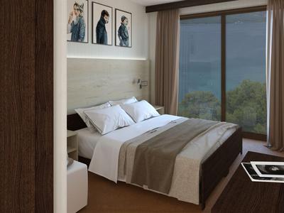 Accogliente camera d'hotel con letto matrimoniale, arredamento moderno e grande finestra con vista su foresta e lago.