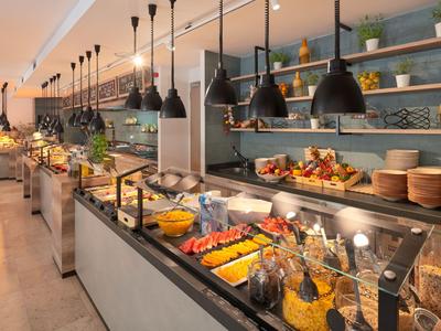 Buffet mit vielfältigen Frühstücksoptionen und moderner Beleuchtung in einem Hotelrestaurant.