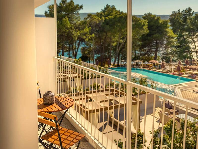 Balcón con dos sillas con vista a una piscina y árboles al fondo.