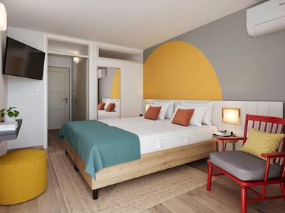 Modernes Schlafzimmer mit großem Doppelbett, grauer Wand, gelbem Halbkreis und rotem Sessel.