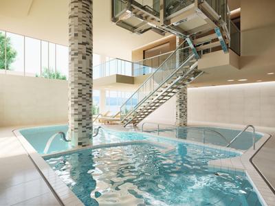 Modernes Hallenbad mit Wasserbecken und Edelstahltreppe in einem hellen Raum.