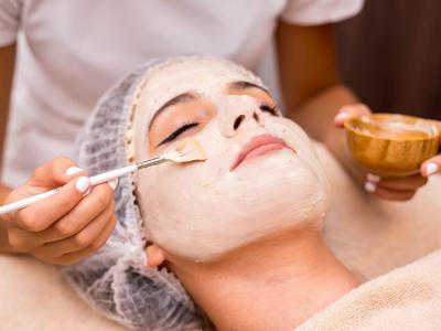 Frau erhält Gesichtsmaske-Behandlung in einem Spa, entspannt mit geschlossenen Augen.