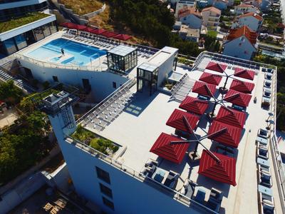 Terrasse sur le toit d'un hôtel avec parasols rouges et piscine à proximité.