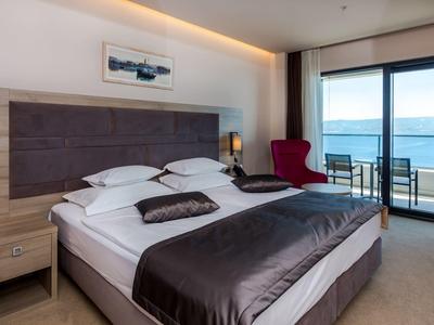 Modernes Hotelzimmer mit Doppelbett, Sitzbereich und Meerblick durch große Fenster